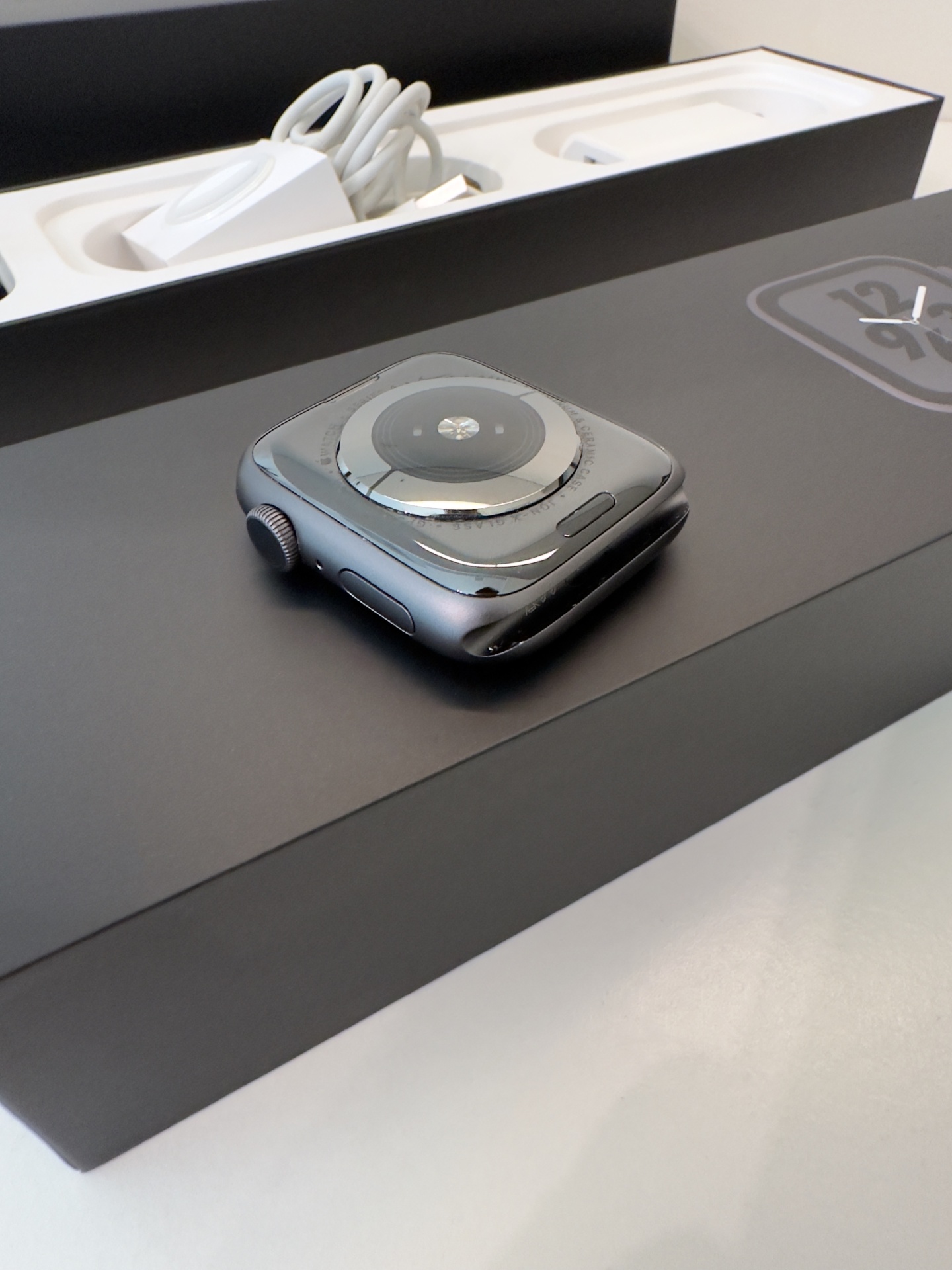 Apple Watch Series 4 Nike+ GPS Space Gray 44mm (de Ocasião) Relógio inteligente preto com mostrador redondo em vidro numa caixa preta e cabo branco