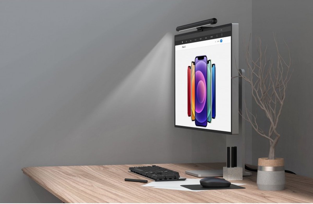 Barra de Luz LED Regulável Rixus Smart Light para Monitor Computador de secretária com monitor vertical, teclado, rato, caneta gráfica e vaso com planta seca numa mesa de madeira clara