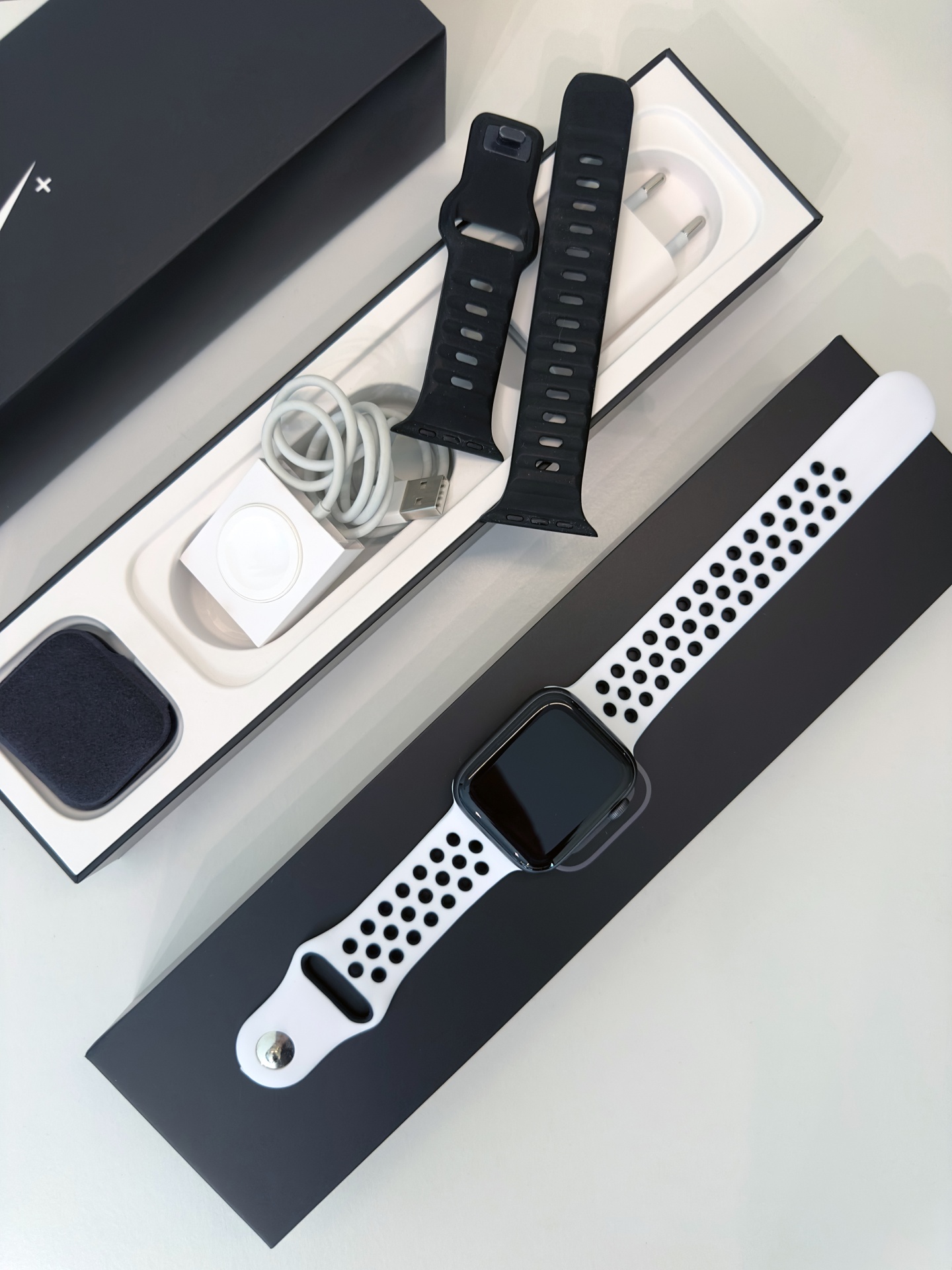 Apple Watch Series 4 Nike+ GPS Space Gray 44mm (de Ocasião) Relógio inteligente com bracelete branca e preta, carregador e acessórios em caixa preta