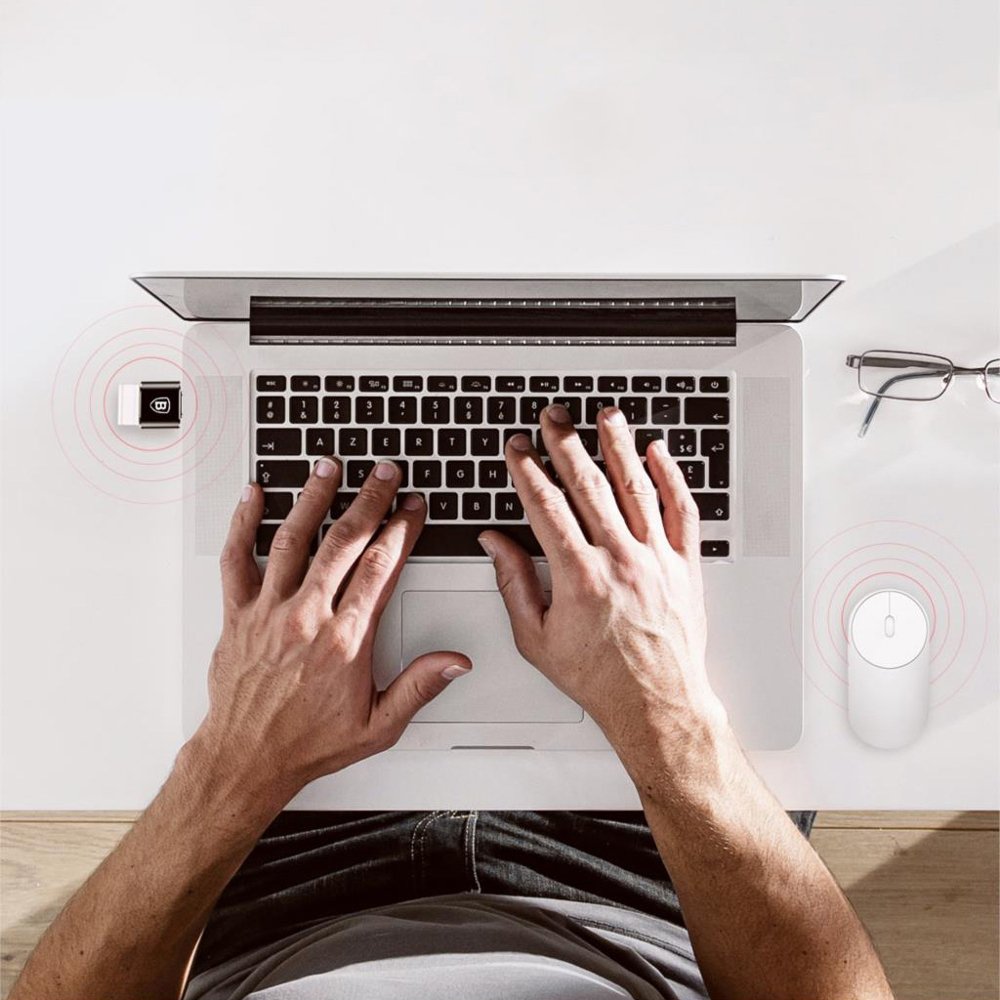 Adaptador USB para USB-C (OTG) Portátil prateado com teclado preto, mãos a digitar, rato branco e óculos numa mesa branca