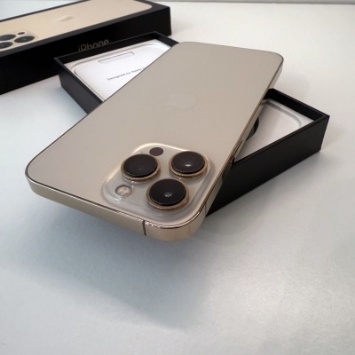 Smartphone dourado com três câmaras sobre caixa preta com desenho de maçã