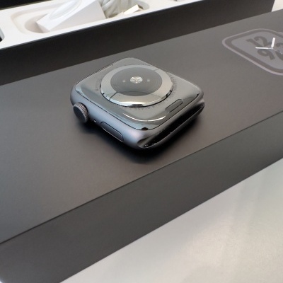 Relógio inteligente preto com mostrador redondo em vidro numa caixa preta e cabo branco