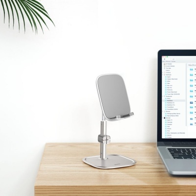 Suporte metálico para telemóvel cinzento em mesa de madeira ao lado de portátil