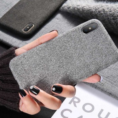 Capa de smartphone cinza de tecido com câmara dupla segurada por mão com unhas pretas e anel prateado