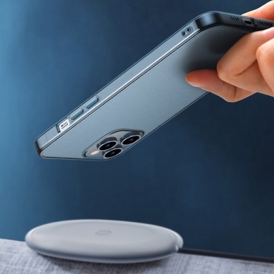 Smartphone cinzento escuro com capa protetora a ser aproximado de um carregador sem fios branco redondo