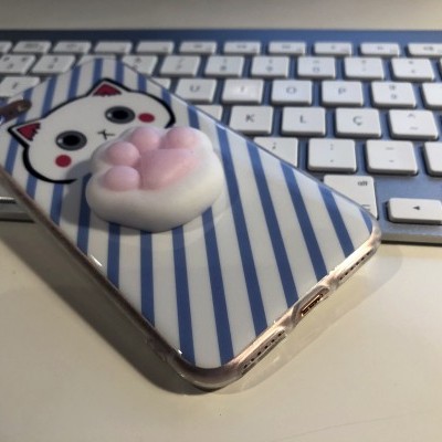 Capa de telemóvel com padrão de gato e pata em relevo sobre teclado branco