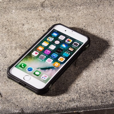 Telemóvel branco com capa preta numa superfície de pedra cinzenta