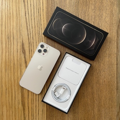 Smartphone Apple iPhone prateado com caixa e acessórios sobre mesa de madeira