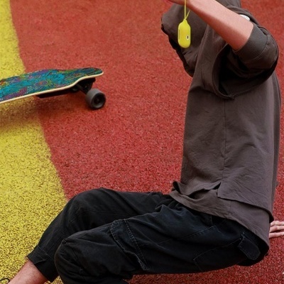 Pessoa com roupa casual e skate em pavimento colorido