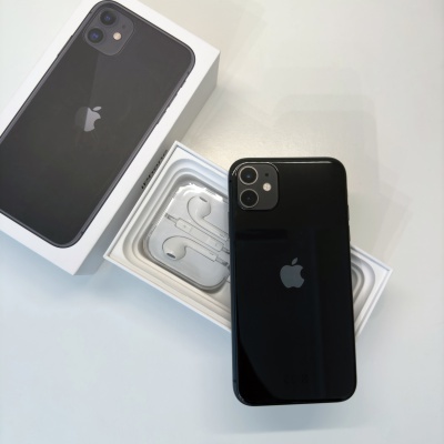 Smartphone preto Apple iPhone ao lado da caixa e auriculares brancos