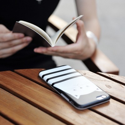 Capa para telemóvel com padrão de listras e rosto minimalista sobre mesa de madeira