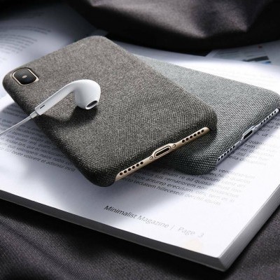 Dois telemóveis com capas de tecido cinzento em cima de um livro aberto com um auricular branco