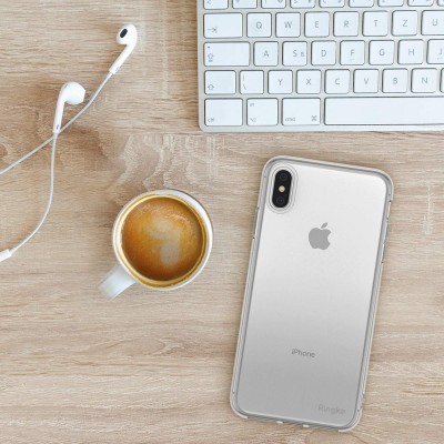 Secretária com teclado branco, auscultadores, café e iPhone prateado com capa transparente
