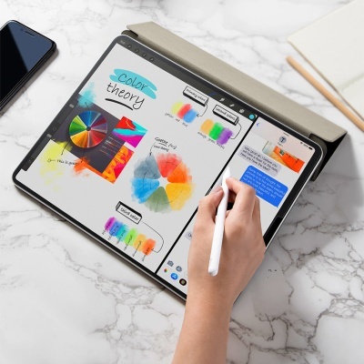 Tablet com caneta digital mostrando esquemas de teoria das cores e mensagens, em superfície de mármore com telemóvel e caderno ao lado