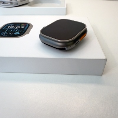 Relógio inteligente cinza com botão laranja sobre caixa branca