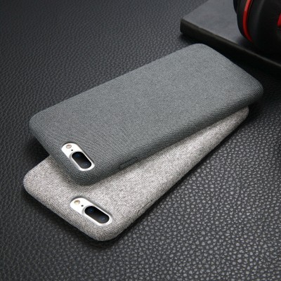 Capas para telemóvel em tecido cinza claras e escuras sobre superfície preta texturizada