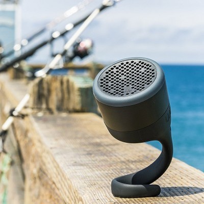 Coluna portátil preta curva numa superfície de madeira junto ao mar com varas de pesca no fundo