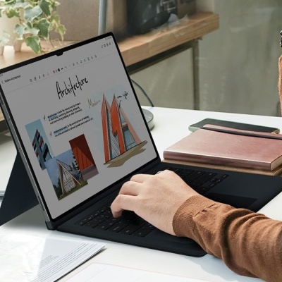 Portátil preto em modo tablet com teclado numa secretária branca junto a uma janela