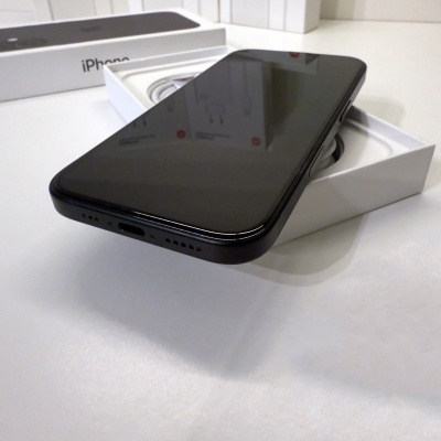 Smartphone preto na caixa aberta com carregadores ao fundo