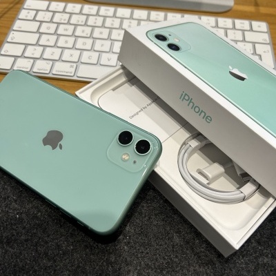 iPhone verde menta com caixa e cabo, teclado branco ao fundo