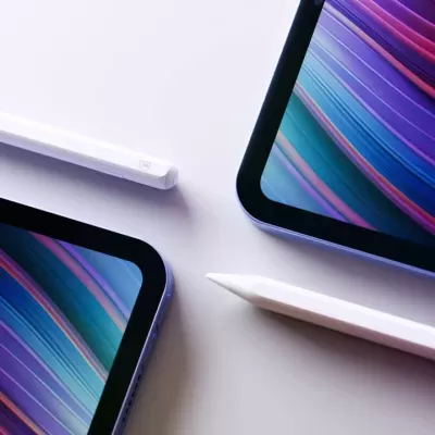 Dois tablets com ecrãs coloridos e duas canetas digitais brancas sobre superfície branca