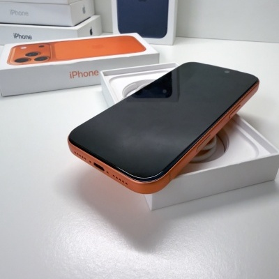 Smartphone iPhone laranja sobre caixa branca com texto iPhone em laranja e outras caixas ao fundo