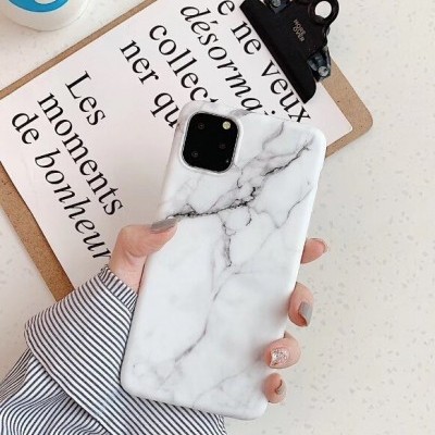 Telemóvel com capa branca de padrão mármore em mão sobre mesa com prancheta e texto em francês