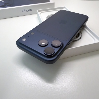 Smartphone iPhone preto com três câmaras atrás em cima de caixa branca com o texto iPhone