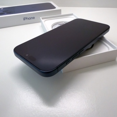 Smartphone preto com visor desligado em cima de caixa branca aberta com cabo branco e caixa maior com texto iPhone.