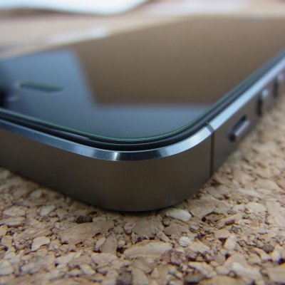 Canto de smartphone preto com ecrã espelhado sobre superfície de cortiça