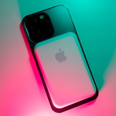 iPhone preto com três câmaras e uma capa ou caixa branca da Apple sobre superfície branca