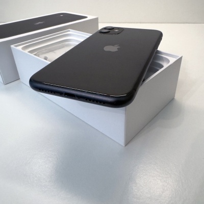 Smartphone preto Apple sobre caixa branca aberta em superfície branca