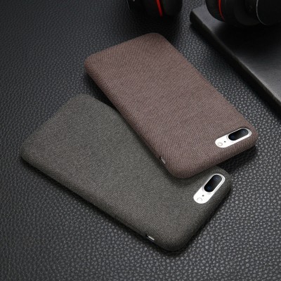 Dois telemóveis com capas de tecido castanho claro e cinza escuro sobre superfície preta texturizada e auscultador preto