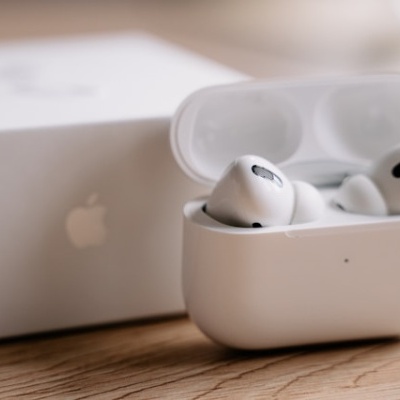 Auriculares sem fios Apple AirPods Pro em estojo branco sobre superfície de madeira com caixa branca ao fundo