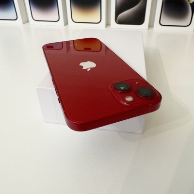 iPhone vermelho com duas câmaras sobre caixa branca e caixas de iPhones ao fundo
