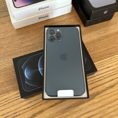 iPhone preto com três câmaras na traseira numa caixa preta sobre uma mesa de madeira clara