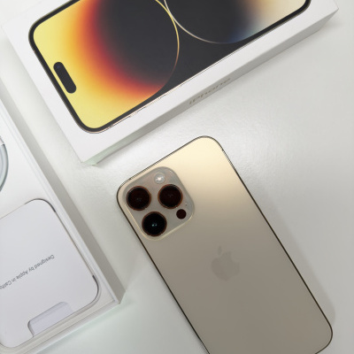 Smartphone dourado com três câmaras e caixa branca com imagem do ecrã