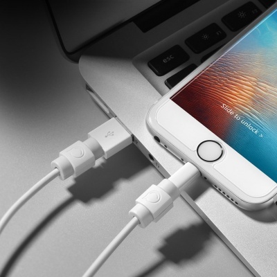 Cabo branco USB conectado a portátil e telefone branco com ecrã ligado