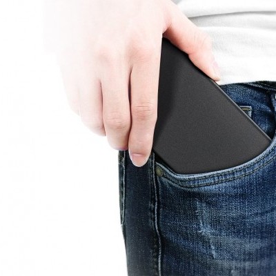 Pessoa a colocar smartphone preto no bolso de calças de ganga azul escura.