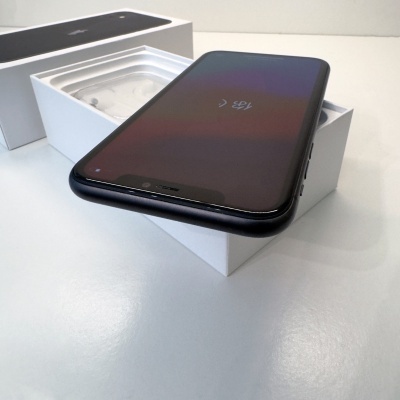 Smartphone preto deitado em caixa branca com auriculares