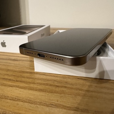 Smartphone cinzento com bordas metálicas em caixa branca e caixa do iPhone com logótipo da Apple.