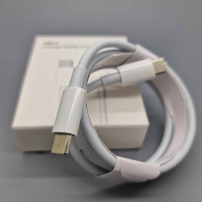 Cabo USB tipo C branco sobre superfície cinzenta com caixa branca desfocada ao fundo