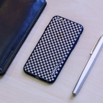 Telemóvel com capa padrão xadrez preto e branco ao lado de caneta prateada e estojo preto