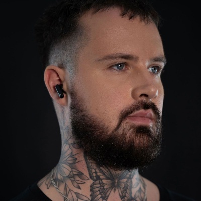 Homem com auriculares wireless pretos e tatuagens no pescoço