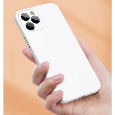 Telemóvel com capa branca e três lentes, segurado por uma mão em fundo laranja claro