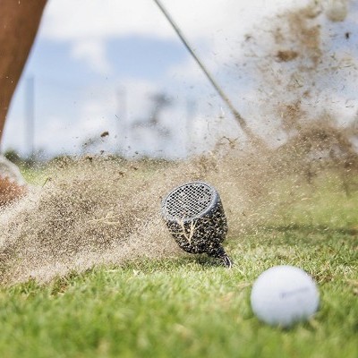 Raquete de golfe a bater numa bola na relva com areia a levantar-se
