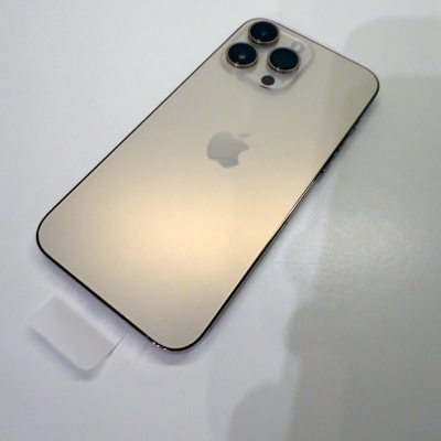 Smartphone dourado da Apple com três câmaras traseiras sobre superfície branca