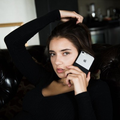 Mulher sentada no sofá a segurar smartphone Apple com capa preta e cinza