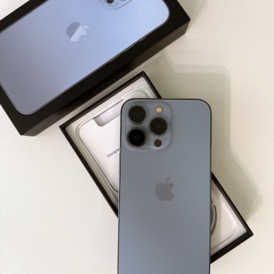 Smartphone Apple iPhone azul claro com três câmeras em cima da embalagem branca e preta