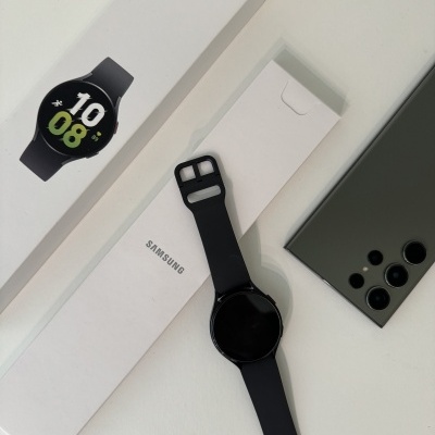 Smartwatch Samsung Galaxy Watch5 preto junto a embalagem e smartphone preto com quatro câmaras traseiras
